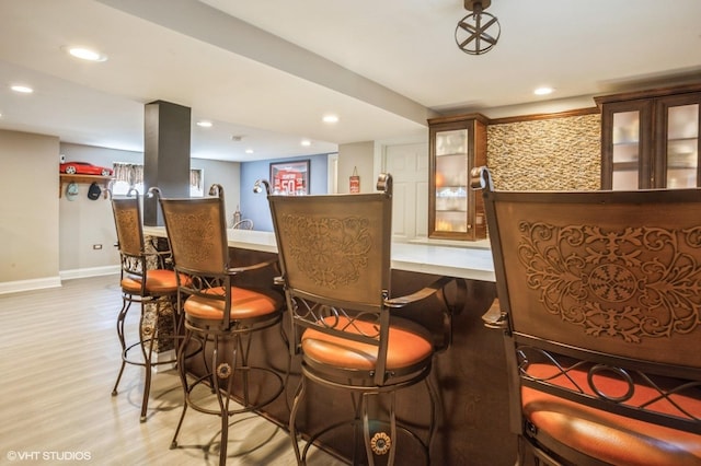 bar with recessed lighting, baseboards, a dry bar, and light wood finished floors