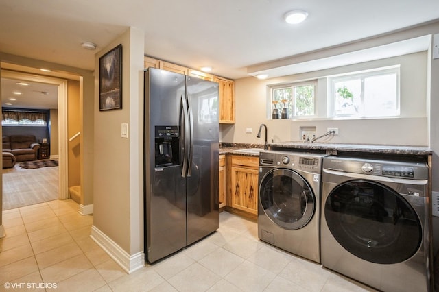 clothes washing area featuring light tile patterned floors, baseboards, laundry area, a sink, and independent washer and dryer