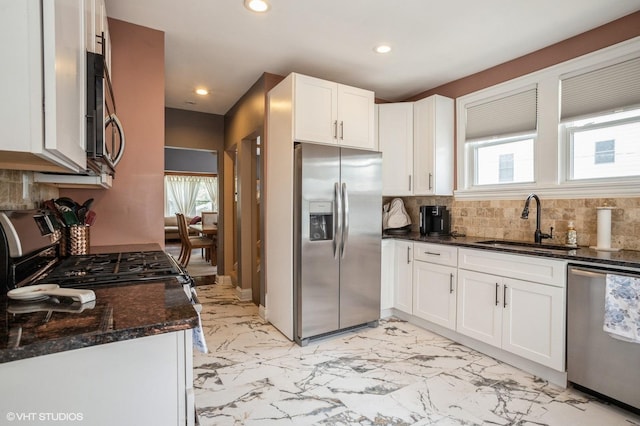 kitchen featuring dark stone counters, appliances with stainless steel finishes, marble finish floor, white cabinetry, and a sink