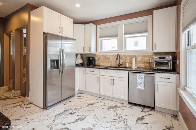 kitchen featuring backsplash, marble finish floor, appliances with stainless steel finishes, and a sink