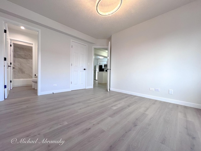 unfurnished bedroom featuring wood finished floors, baseboards, and a textured ceiling