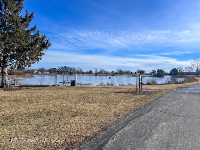 view of dock with a lawn and a water view