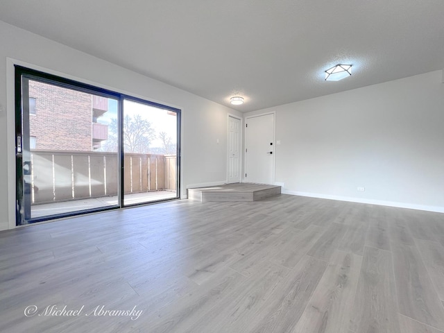 unfurnished living room featuring wood finished floors and baseboards