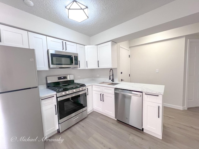 kitchen featuring white cabinetry, light wood-style flooring, appliances with stainless steel finishes, and a sink