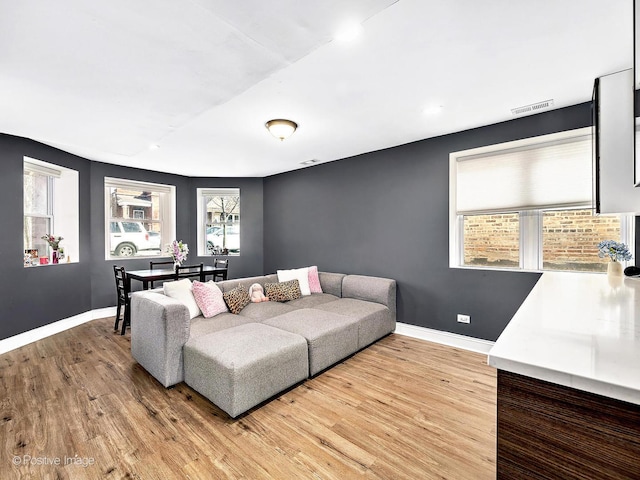 living room featuring visible vents, light wood-type flooring, and baseboards