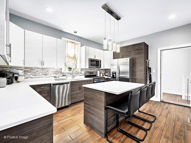 kitchen with a kitchen breakfast bar, stainless steel appliances, light wood-type flooring, and light countertops