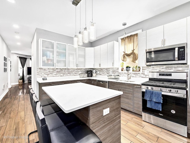 kitchen featuring backsplash, light countertops, a kitchen breakfast bar, light wood-style floors, and stainless steel appliances