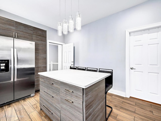 kitchen featuring light wood-style flooring, a breakfast bar area, light countertops, and stainless steel refrigerator with ice dispenser