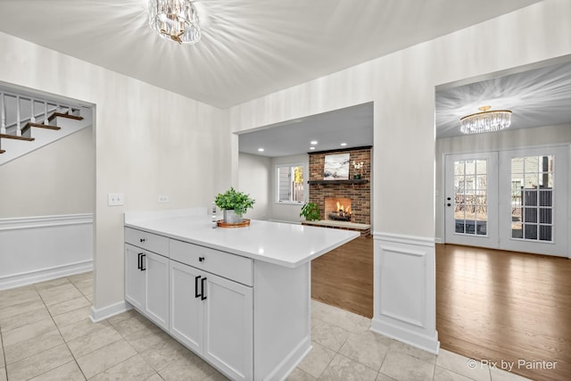 kitchen with light countertops, a notable chandelier, a fireplace, and light tile patterned floors