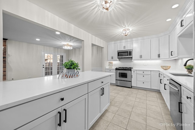 kitchen with a sink, light countertops, appliances with stainless steel finishes, white cabinetry, and a chandelier