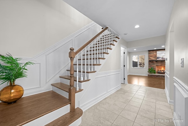 stairway with tile patterned floors, recessed lighting, a fireplace, and a decorative wall