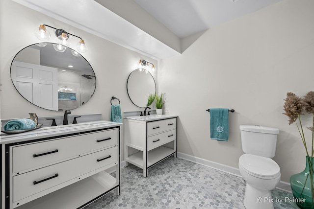 full bath featuring a sink, toilet, baseboards, and two vanities