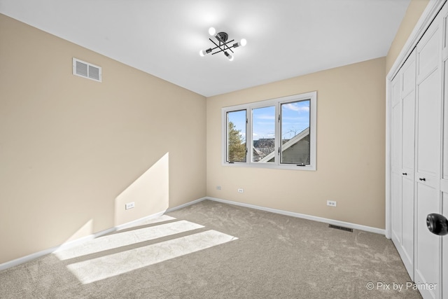 unfurnished bedroom with light carpet, visible vents, baseboards, and a closet