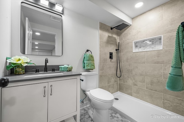 full bathroom featuring tiled shower, toilet, vanity, and visible vents