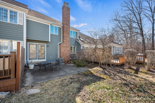 back of house featuring central AC unit, a patio area, and a chimney