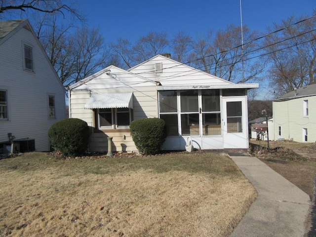 view of front facade with central AC, a front lawn, and a sunroom