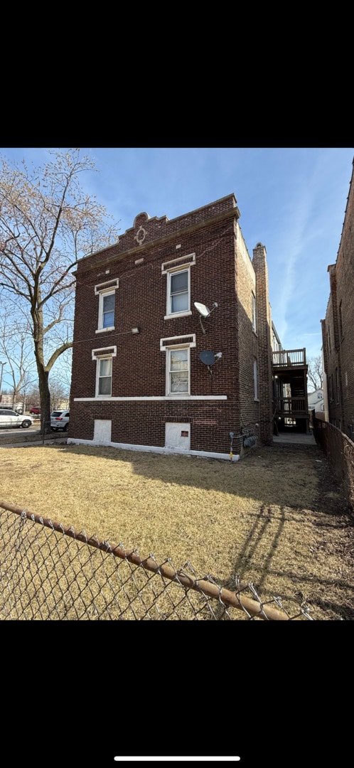 back of property featuring fence and brick siding