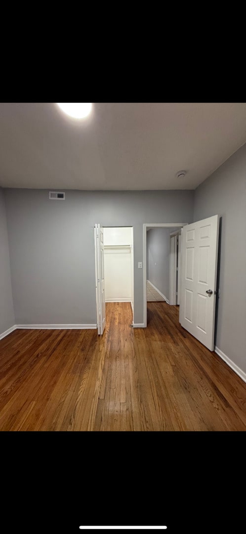 empty room featuring visible vents, baseboards, and wood finished floors