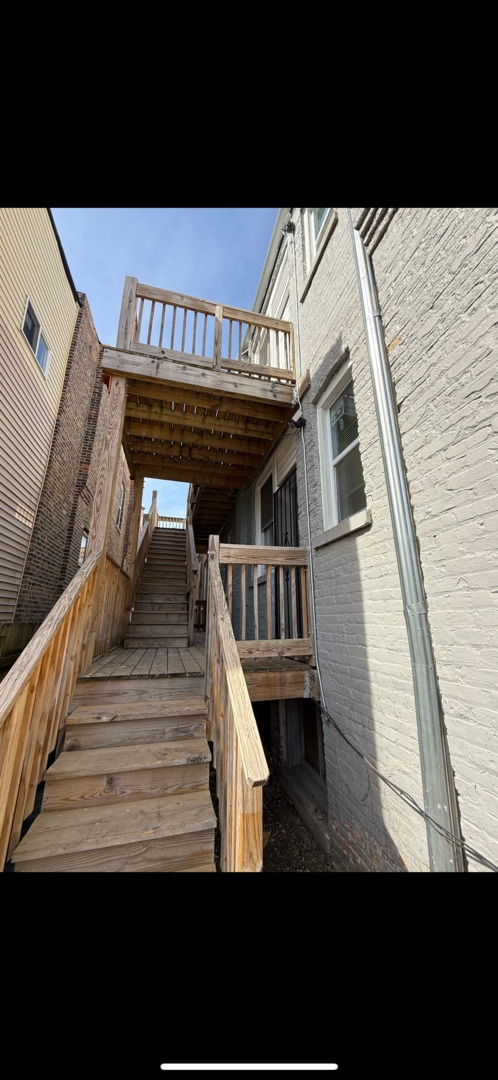 exterior space featuring brick siding, stairway, and a wooden deck