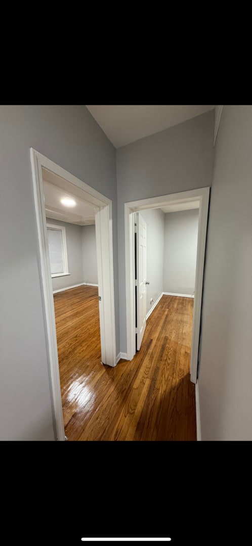 corridor featuring baseboards and wood finished floors