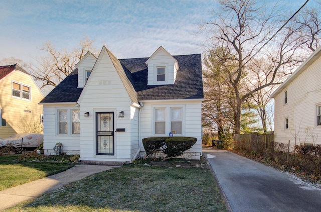 view of front of house featuring a front lawn, fence, and a shingled roof