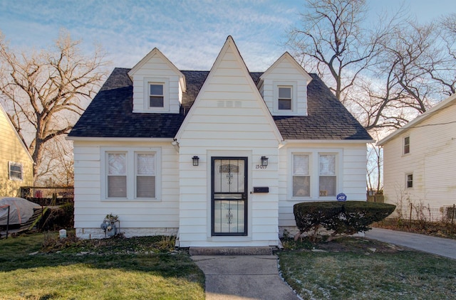 cape cod house with a front lawn and a shingled roof