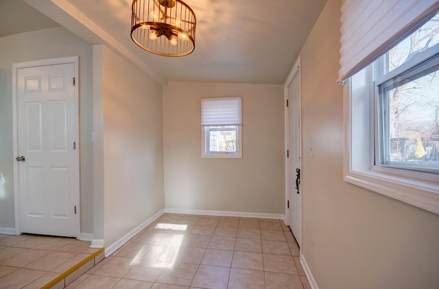 foyer entrance with a notable chandelier, light tile patterned flooring, and baseboards