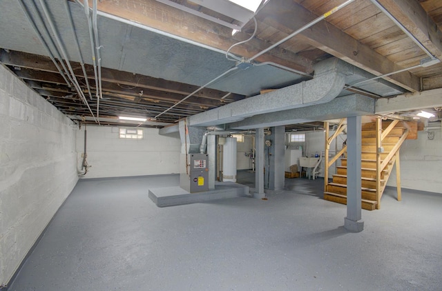 below grade area featuring stairway, heating unit, and a sink