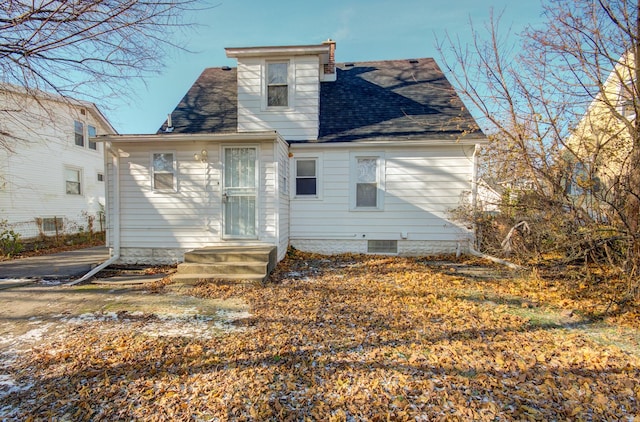 rear view of house featuring a shingled roof and a chimney