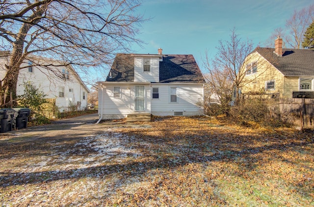 rear view of property with entry steps, a chimney, and fence