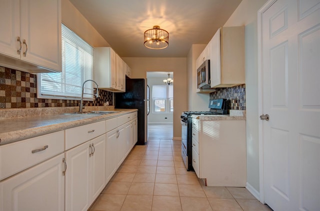 kitchen with a sink, appliances with stainless steel finishes, light countertops, light tile patterned floors, and a chandelier