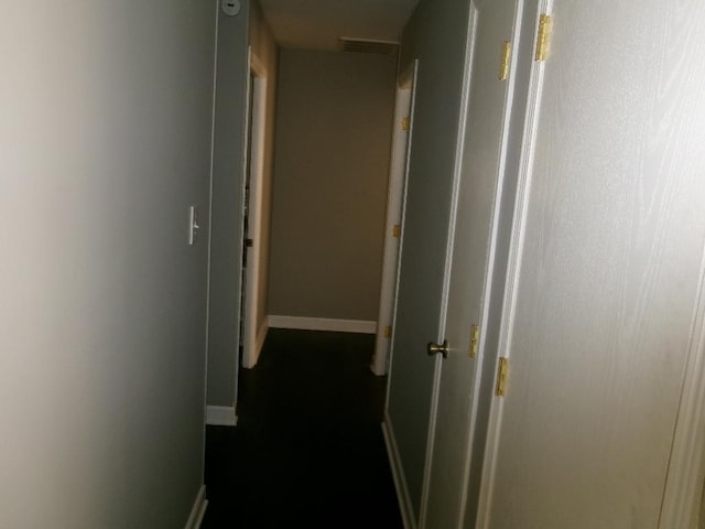 hallway featuring baseboards and visible vents