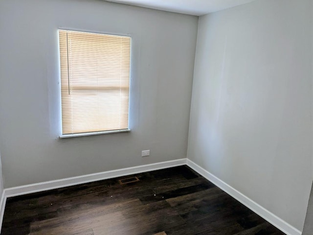 unfurnished room with dark wood-style flooring, baseboards, and visible vents