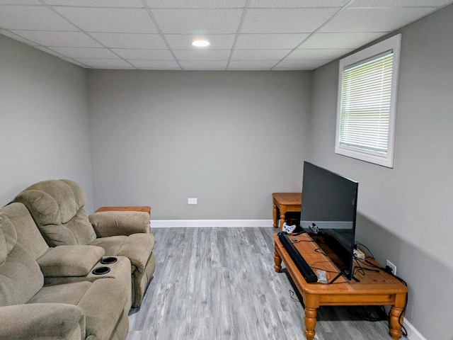 living room featuring baseboards, a paneled ceiling, and wood finished floors