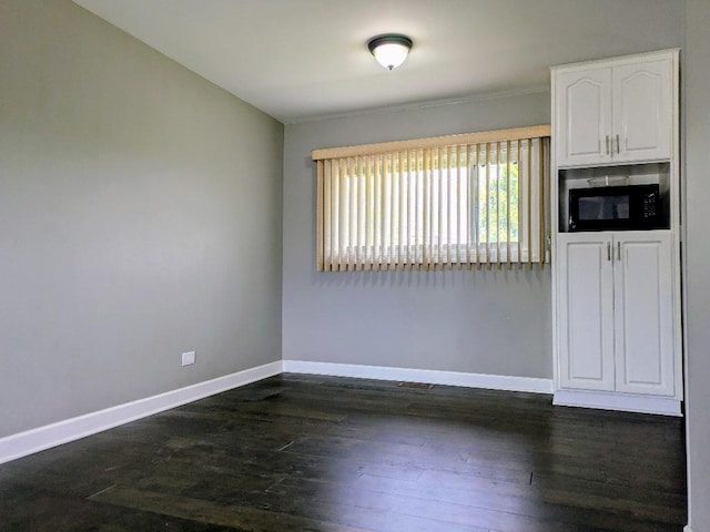 empty room featuring baseboards and dark wood-type flooring
