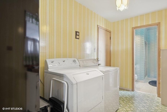 laundry area with light floors, baseboards, washing machine and clothes dryer, wallpapered walls, and laundry area