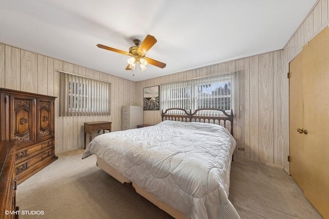 bedroom featuring light carpet, ceiling fan, and wood walls