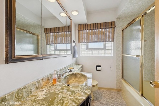 full bath featuring vanity, toilet, a healthy amount of sunlight, and combined bath / shower with glass door