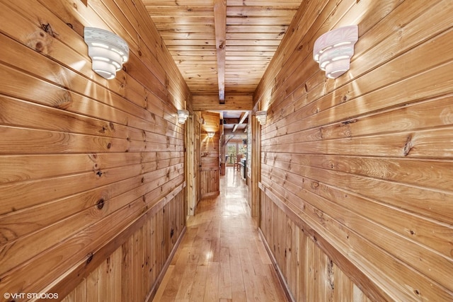 hall featuring wooden walls, wood ceiling, and light wood-type flooring