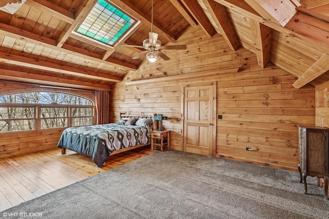 unfurnished bedroom featuring wooden walls, carpet, vaulted ceiling with skylight, wooden ceiling, and wood finished floors