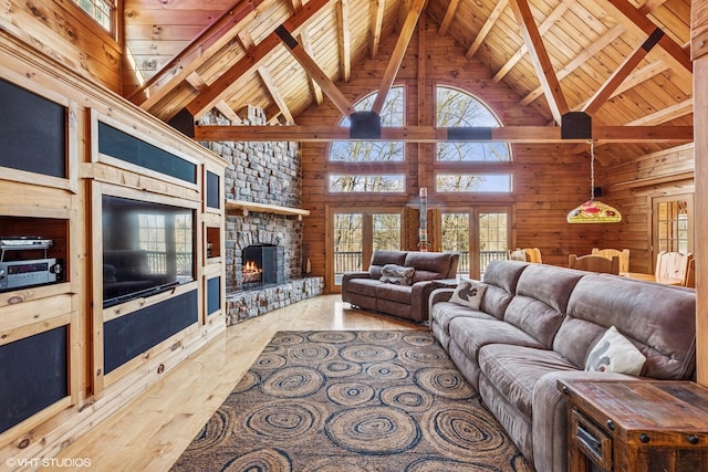 living area featuring wood walls, wood ceiling, lofted ceiling with beams, a stone fireplace, and wood finished floors