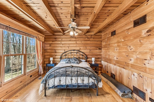 bedroom featuring beamed ceiling, visible vents, hardwood / wood-style flooring, rustic walls, and wood ceiling