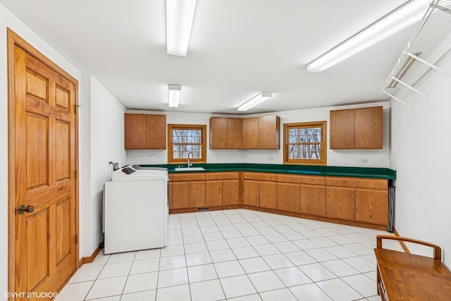 kitchen featuring visible vents, a sink, brown cabinetry, light tile patterned floors, and washer / dryer