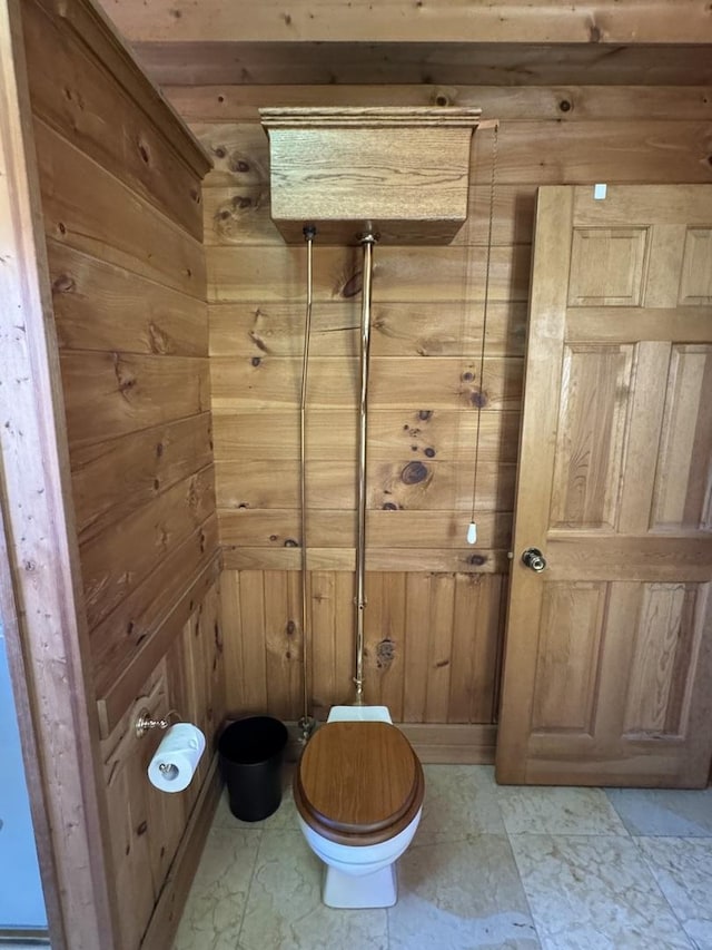 bathroom with toilet and wood walls