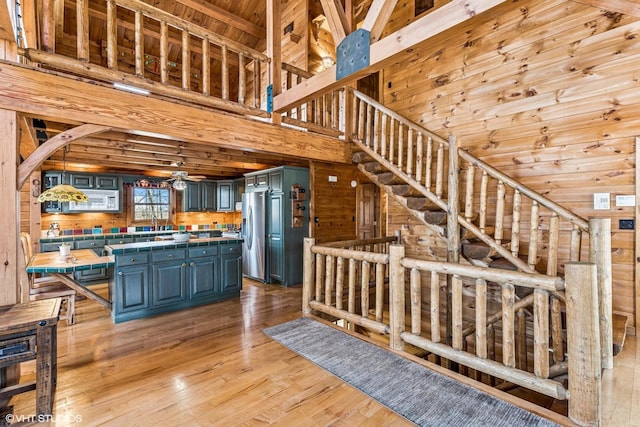 kitchen featuring tile counters, stainless steel fridge with ice dispenser, light wood-style floors, and wood walls