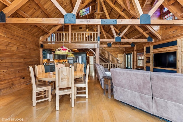 dining room featuring wooden walls, stairs, wood-type flooring, wooden ceiling, and beamed ceiling