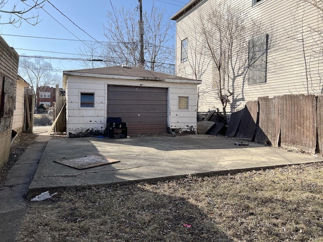 detached garage with concrete driveway and fence