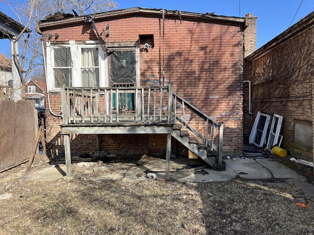 rear view of house featuring a wooden deck, brick siding, stairs, and a sunroom