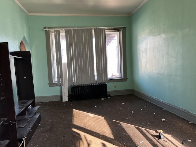 empty room featuring baseboards, ornamental molding, and radiator heating unit