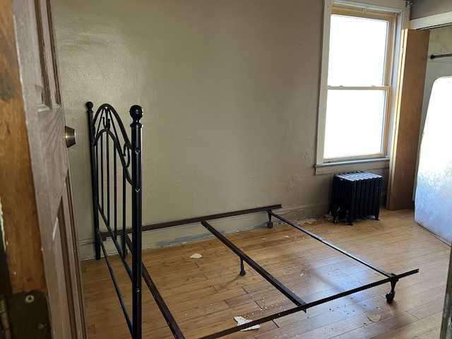 unfurnished bedroom featuring radiator and hardwood / wood-style flooring